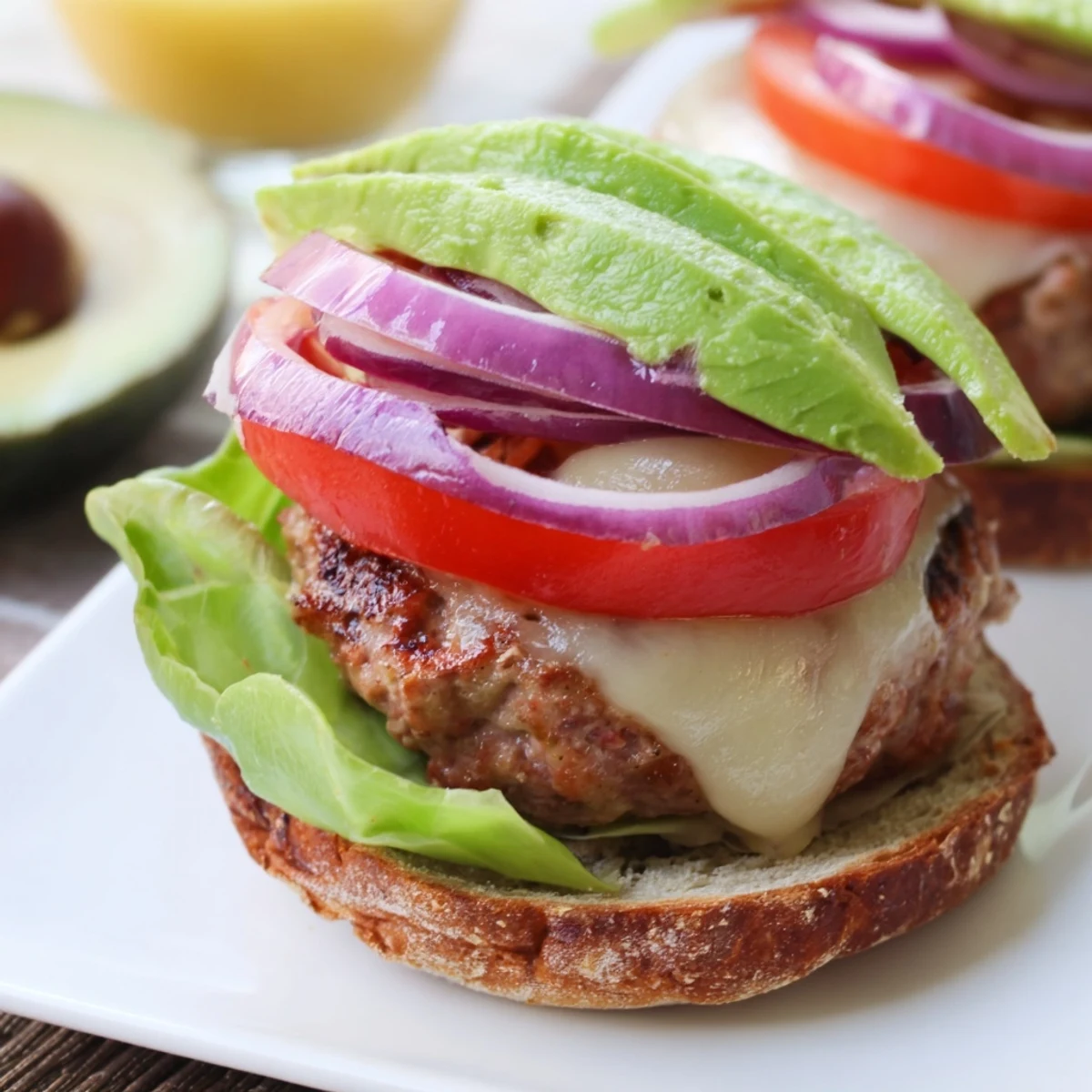 A delicious turkey burger with avocado and melted Swiss cheese, ready to enjoy with a fresh tomato.