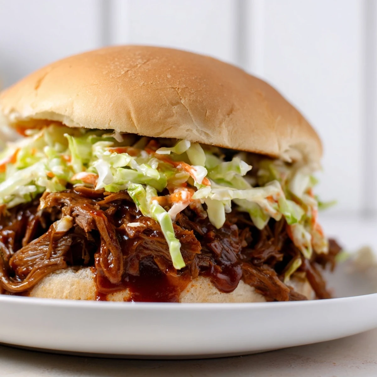 Hearty Slow Cooker Pulled Beef Sandwiches with Slaw ready to serve, showcasing juicy barbecue meat and crunchy vegetable topping on golden toasted rolls.