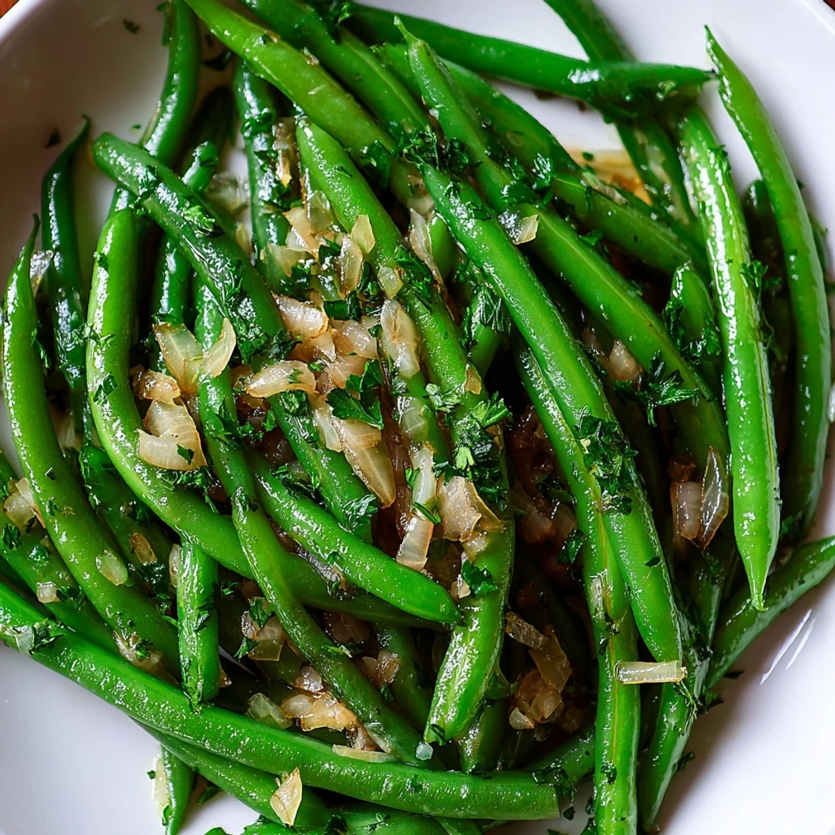 Garlic Butter Green Beans with Shallots glistens with fresh lemon juice and chopped parsley on a simple white plate.