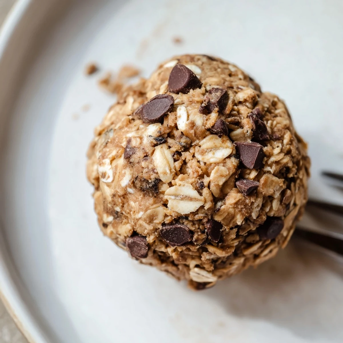 Finger holding a bite-sized Chocolate Peanut Butter Energy ball, revealing a rich, chewy texture with chocolate chips inside.