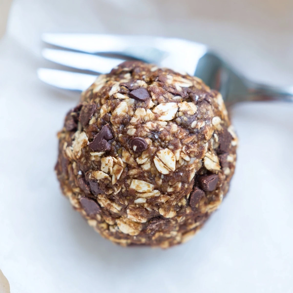 Close-up shot of homemade Chocolate Peanut Butter Energy Balls on a rustic wooden board, showing oats and seeds.