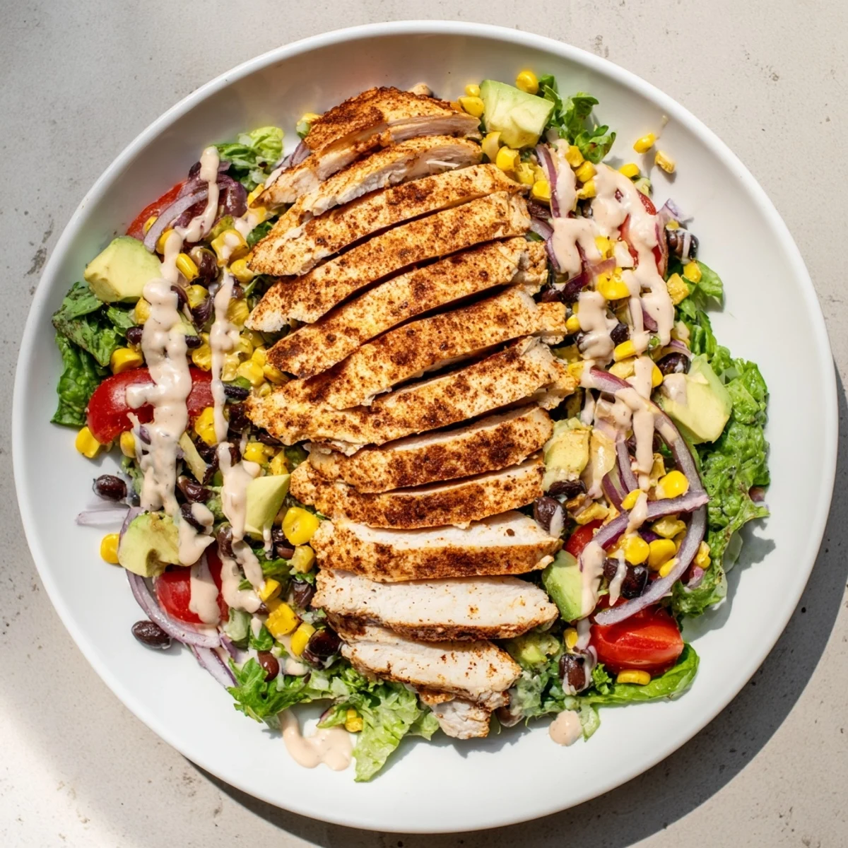 Drizzled with creamy chipotle lime dressing, the Southwest Chicken Salad combines fresh cilantro, shredded cheese, and vibrant veggies on a plate.