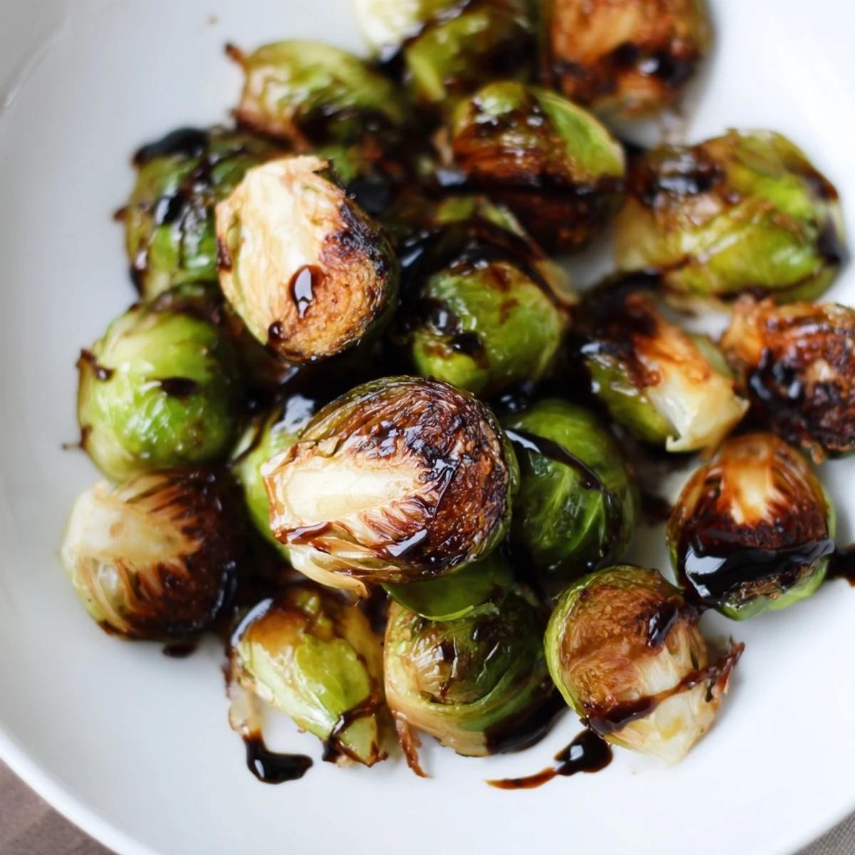 Freshly roasted Brussels sprouts with a sticky-sweet balsamic glaze, garnished with optional chopped walnuts.  