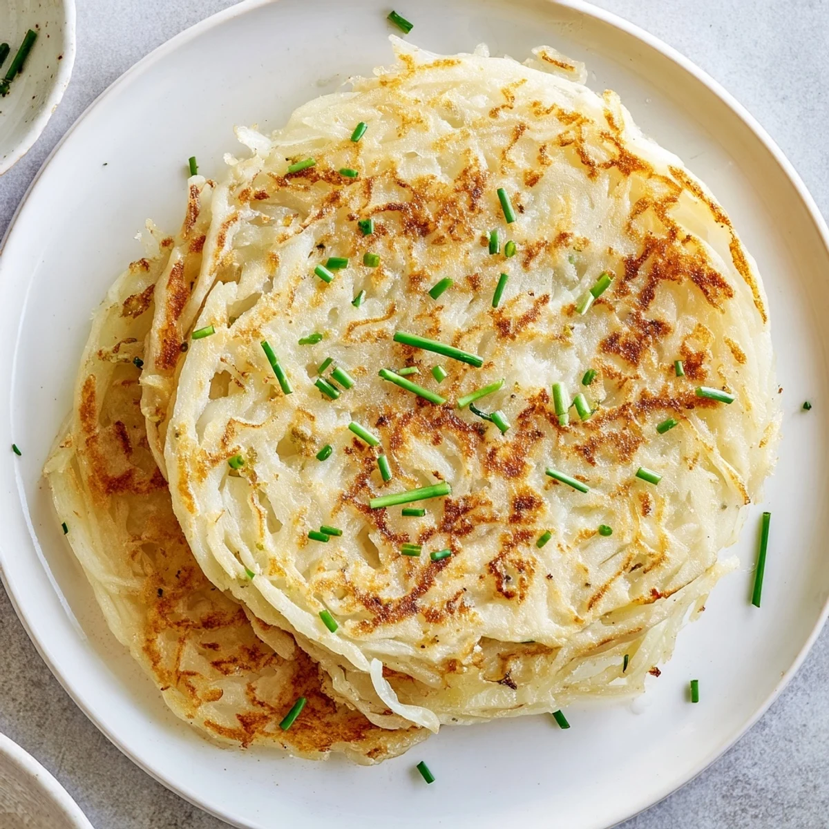 A stack of fresh Irish Boxty Potato Pancakes topped with chives, served alongside sour cream and smoked salmon for a hearty brunch.  