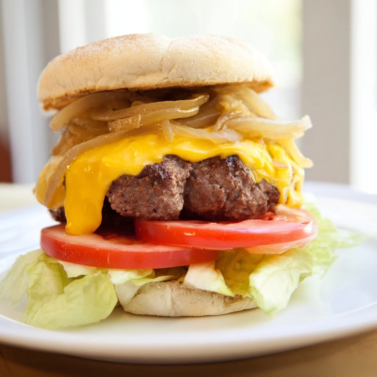 A plated Classic Beef Burger with Caramelized Onions showcases crisp lettuce, tomato, pickles, and a drizzle of ketchup and mustard.