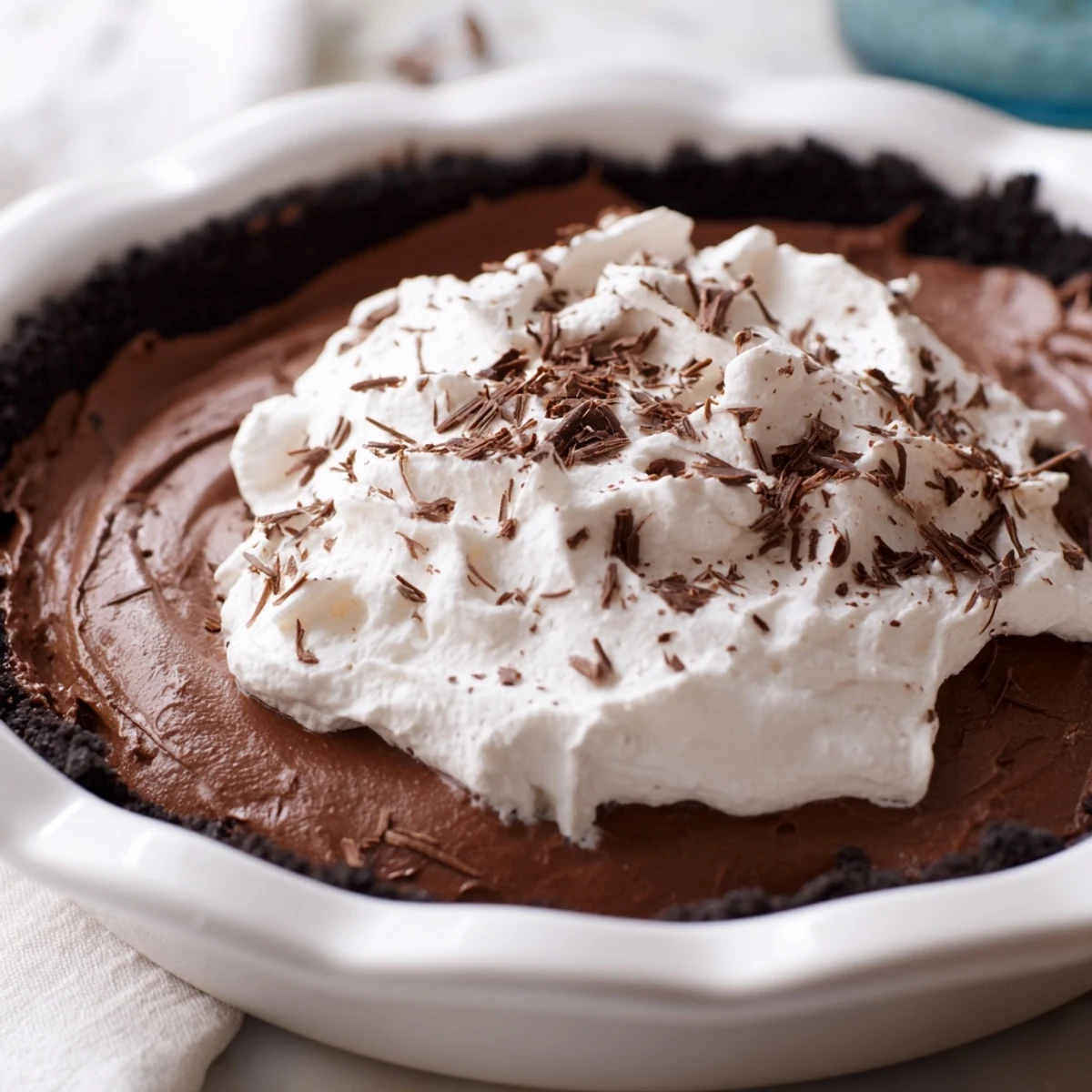 Decadent Chocolate Silk Pie with Whipped Cream in a crisp chocolate cookie crust, topped with fluffy clouds of fresh cream.