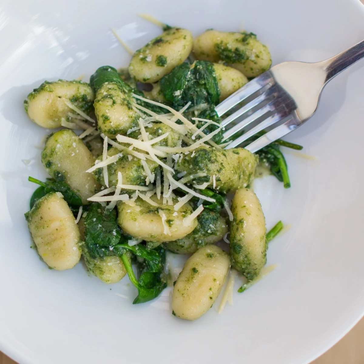 Savory Pesto Gnocchi with Spinach and Parmesan on a rustic wooden board, ready for a weeknight dinner.