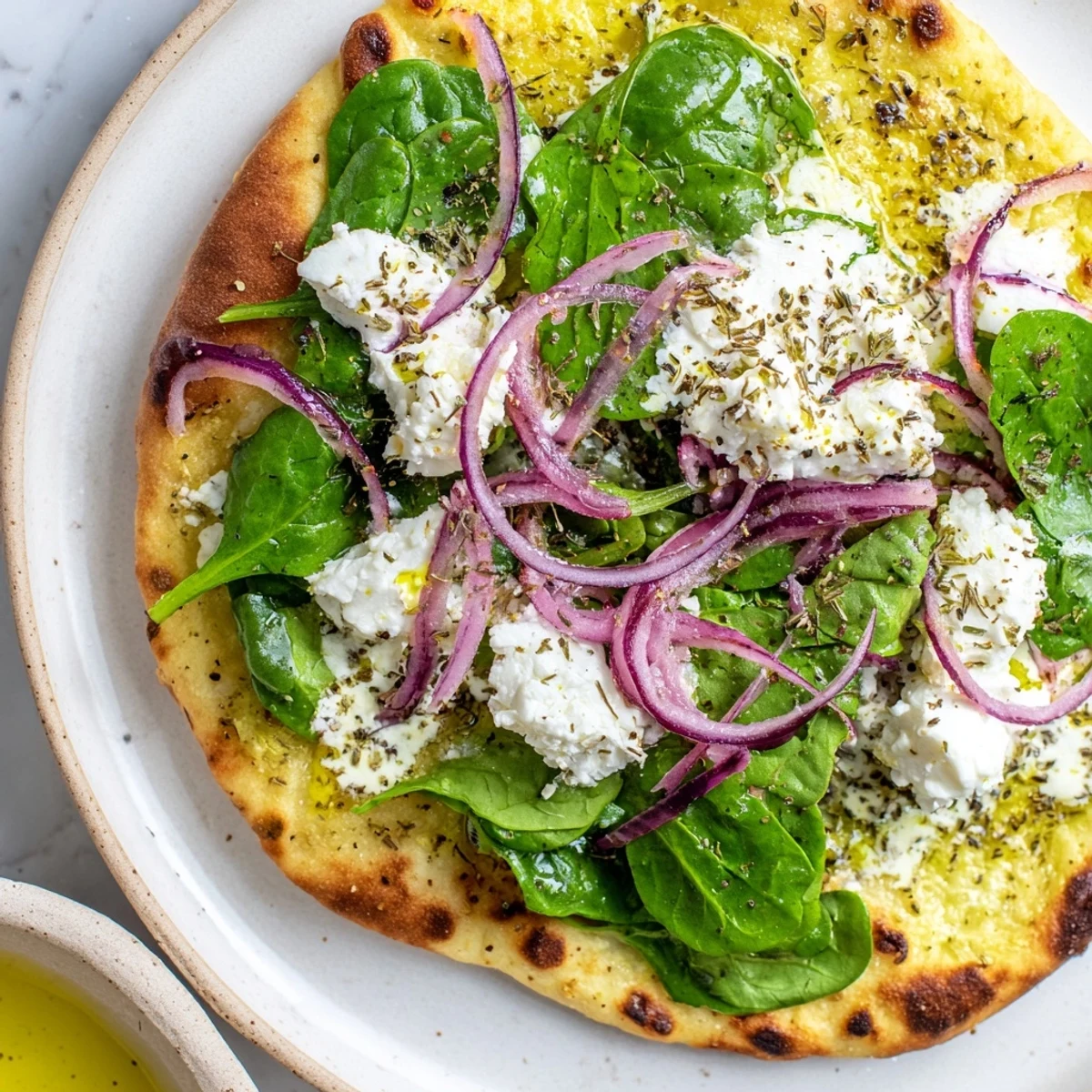 Slice of warm Spinach and Feta Flatbread Pizza on a wooden board, showing melted mozzarella and crumbled feta.
