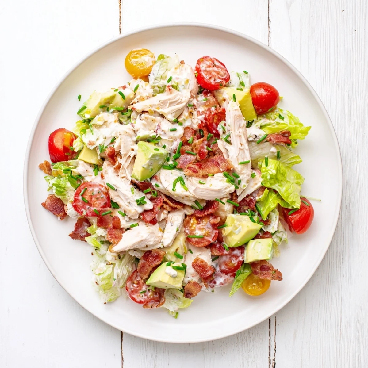 Freshly prepared BLT Chicken Salad with creamy avocado and a tangy dressing, served in a rustic bowl.