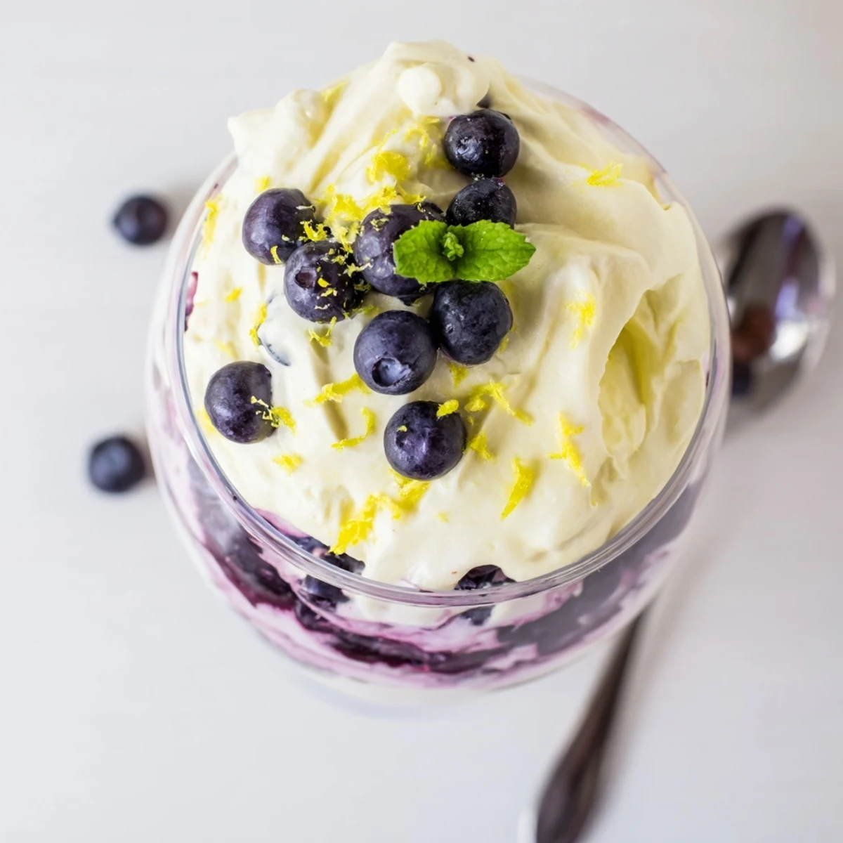 The Lemon Blueberry Mousse is garnished with fresh mint and lemon zest, offering a refreshing and elegant presentation.