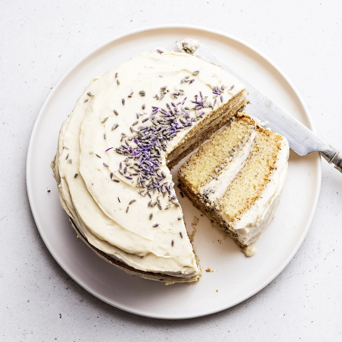 A beautiful London Fog Cake with Earl Grey and Lavender, cut to reveal its tender layers and topped with a drizzle of lavender syrup.