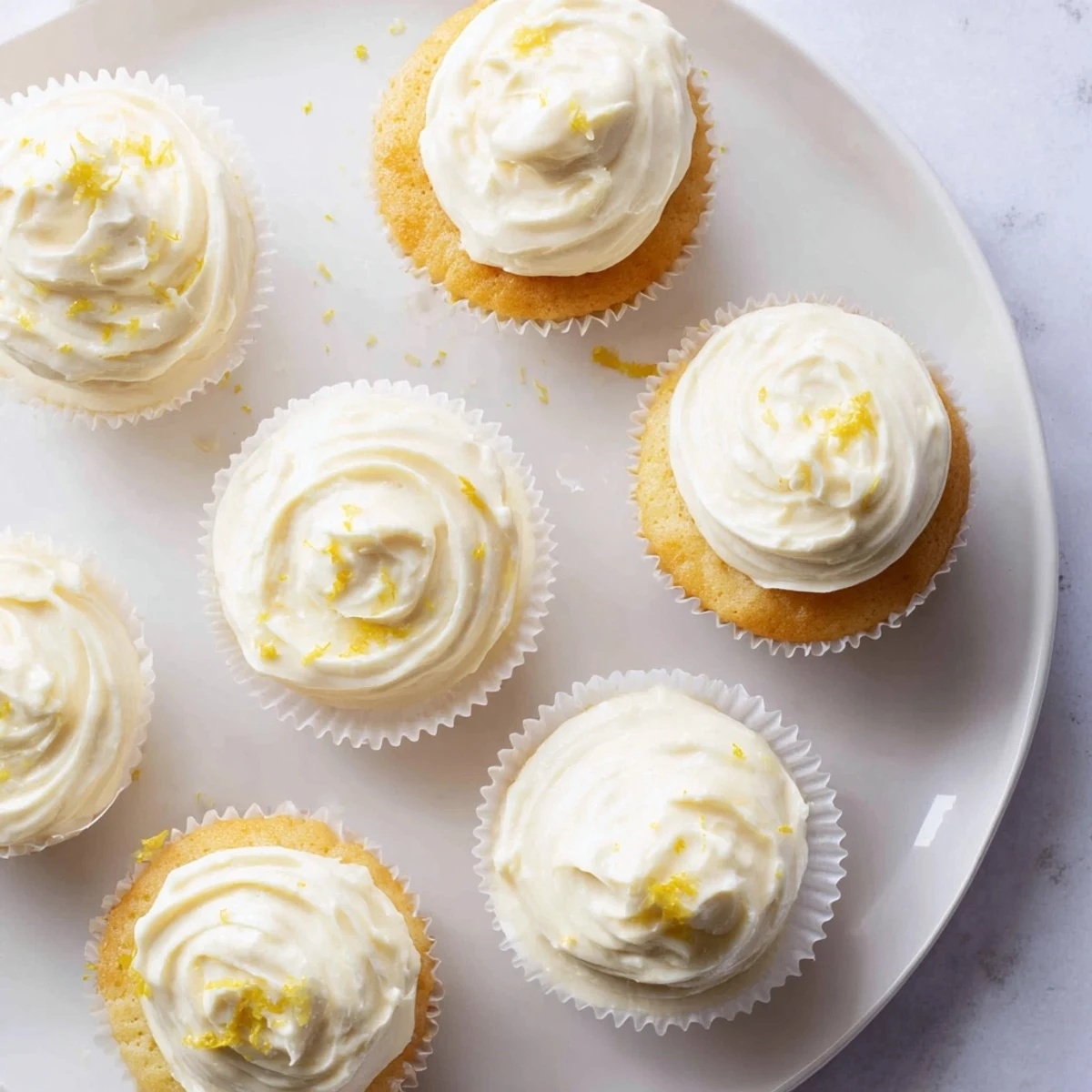 Golden-brown Elderflower Cupcakes topped with swirls of pale buttercream, paired with a steaming cup of tea.