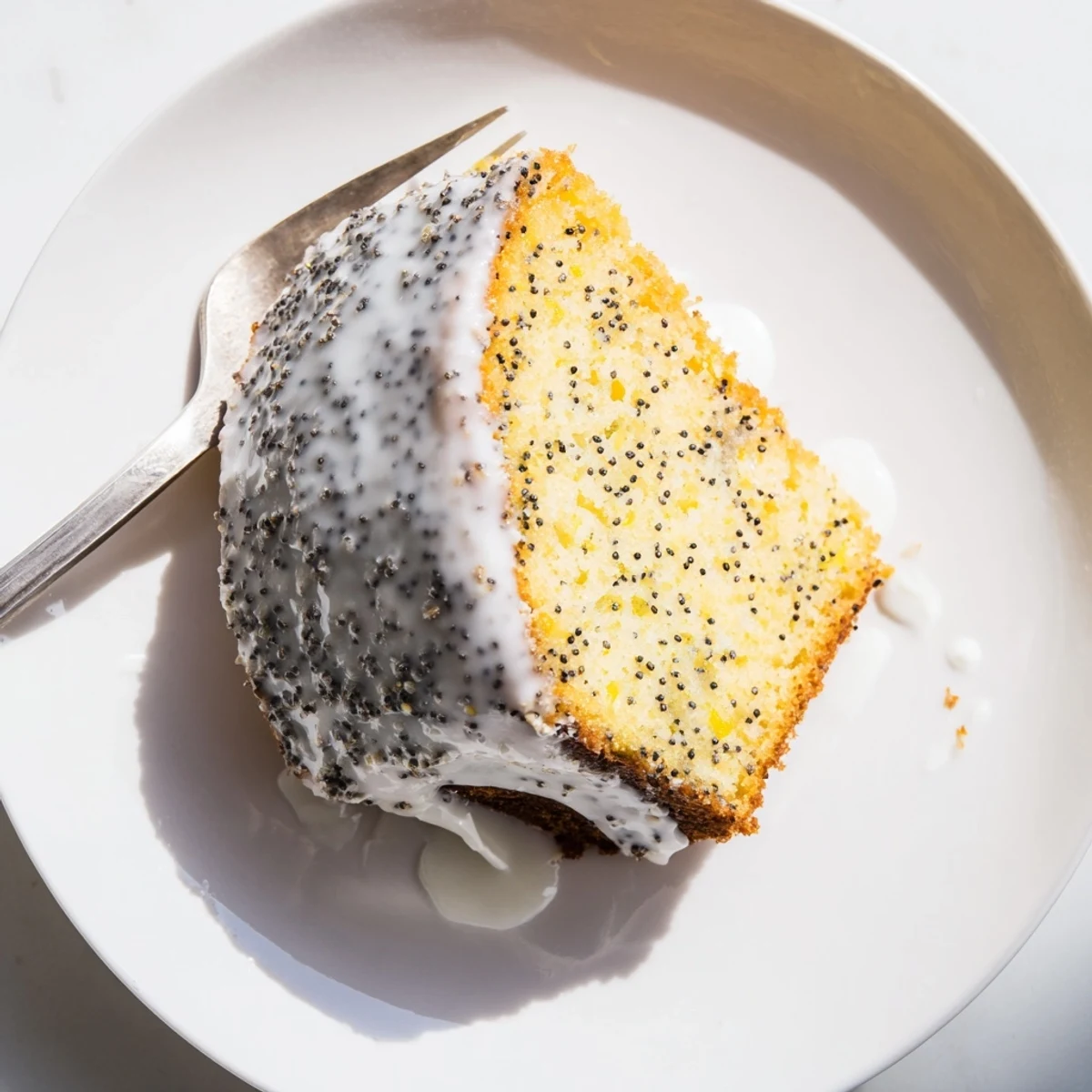 A fresh Lemon Poppy Seed Cake in a Bundt pan is dusted with sugar, displayed beside steaming tea cups.
