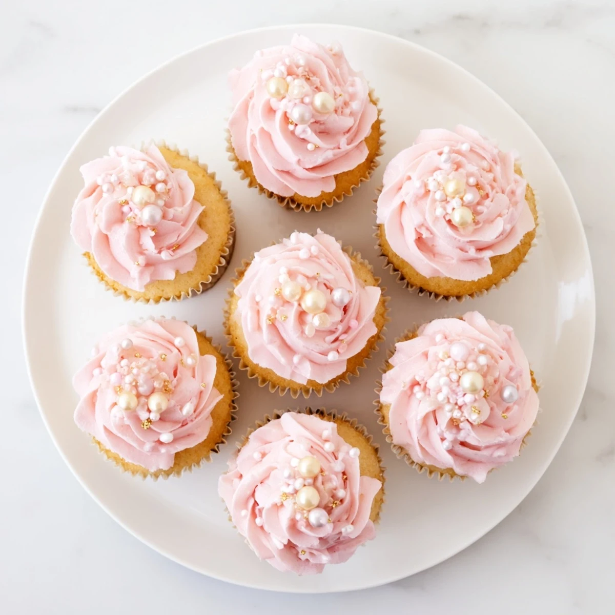 Adorable pink buttercream-topped cupcakes displayed on a white stand for a girl baby shower.