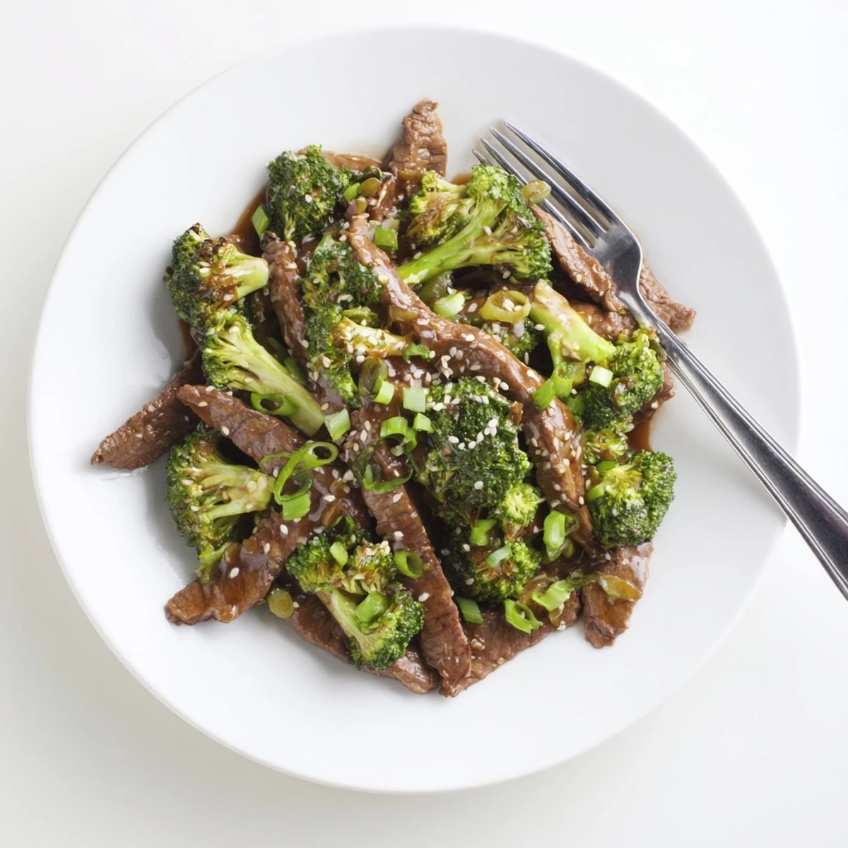 A close-up of Better Than Takeout Beef With Broccoli, with glossy sauce drizzled over steak and crisp broccoli, served over steamed rice.
