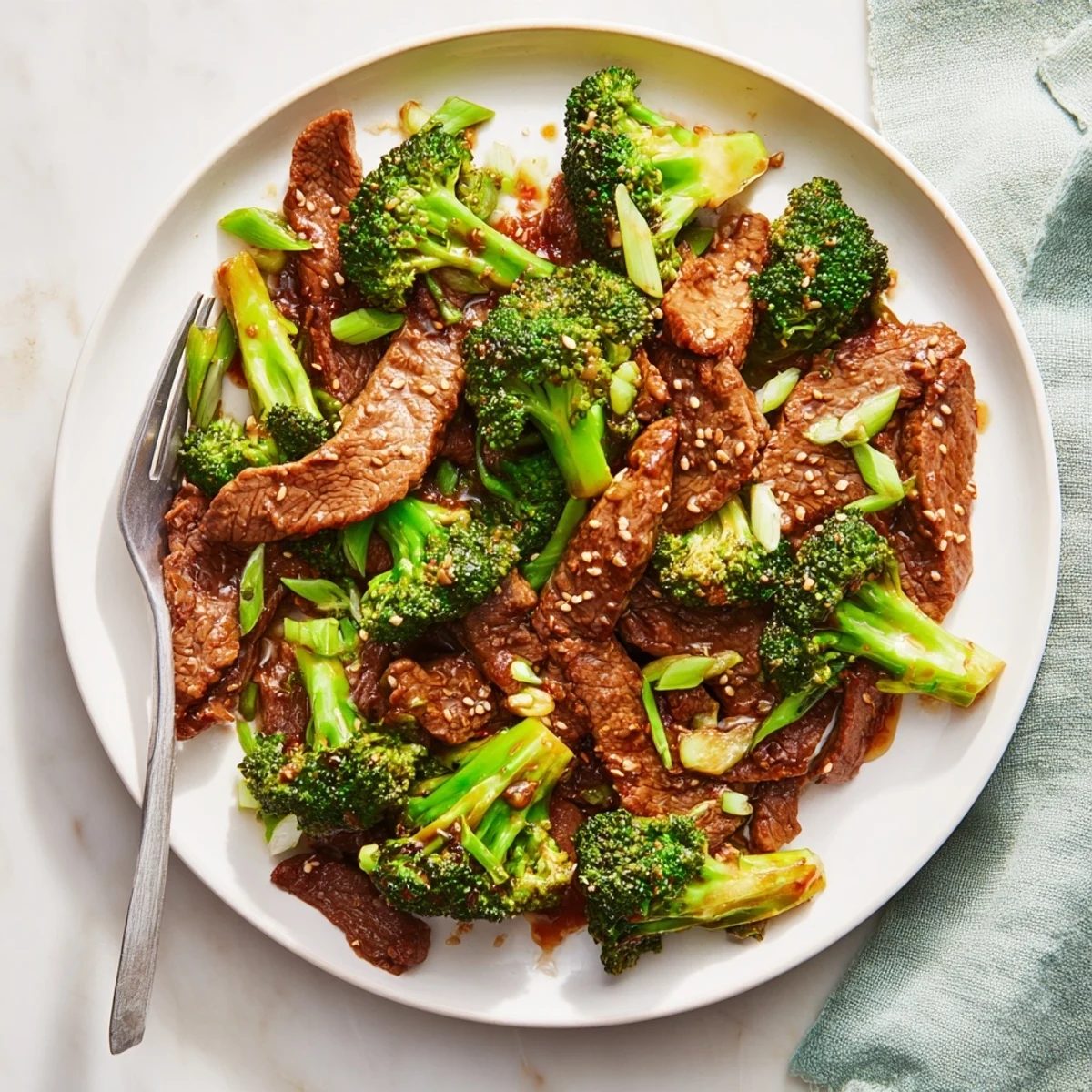 Platter of Better Than Takeout Beef With Broccoli garnished with sesame seeds and green onions, ready for a quick weeknight family dinner.