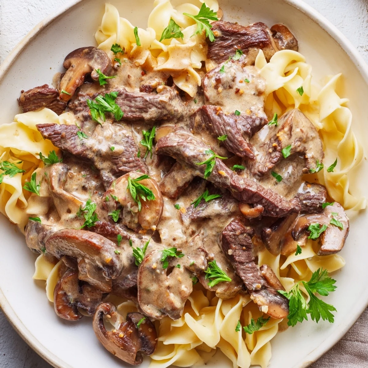 Tender beef strips and earthy mushrooms swim in rich sour cream sauce over noodles