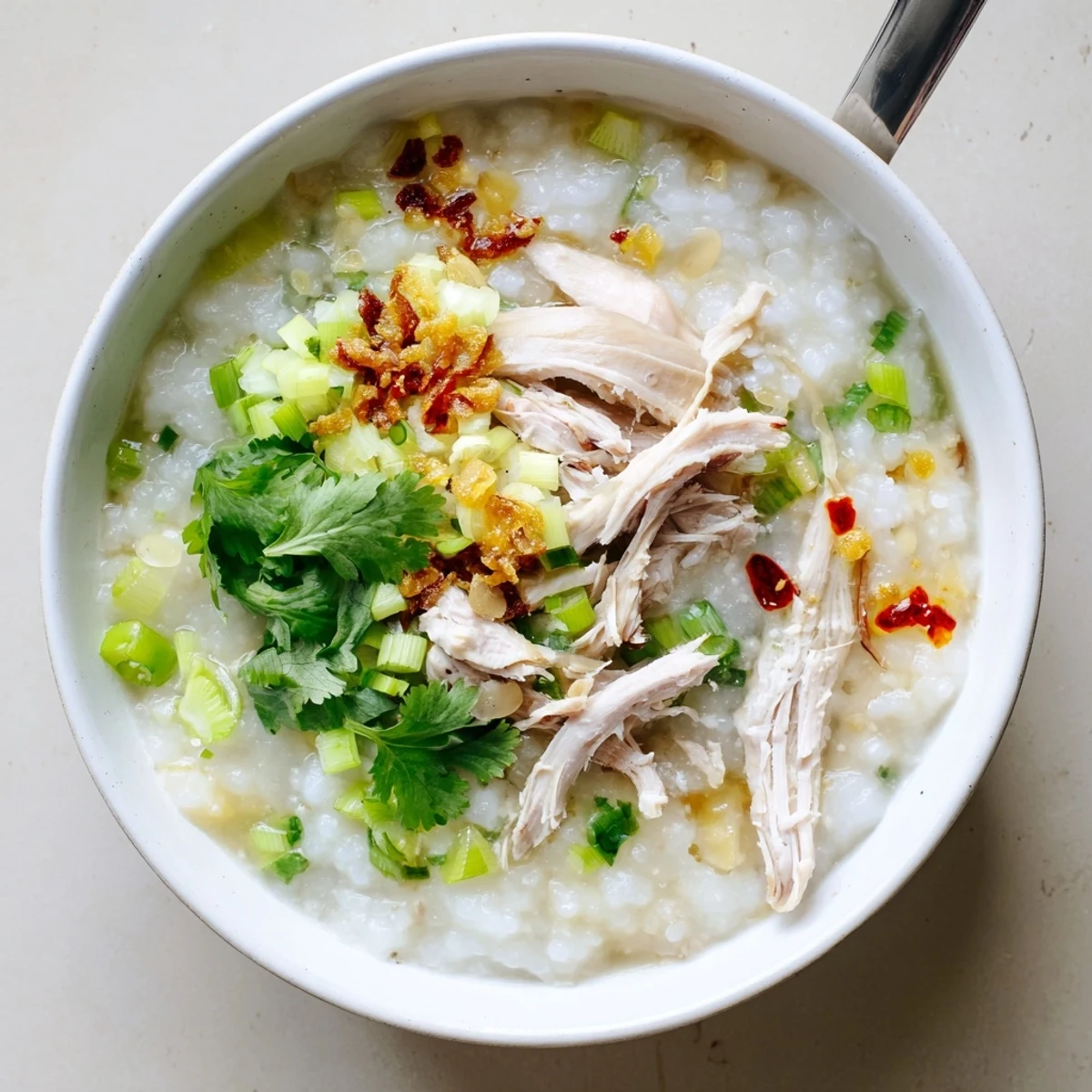Steaming bowl of Asian-style turkey congee garnished with fresh herbs and a perfectly sliced boiled egg