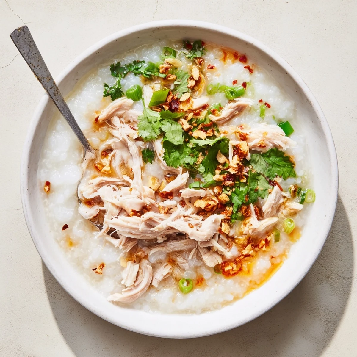 Savory rice porridge with shredded turkey, ginger aromatics, and drizzled chili oil for comforting warmth