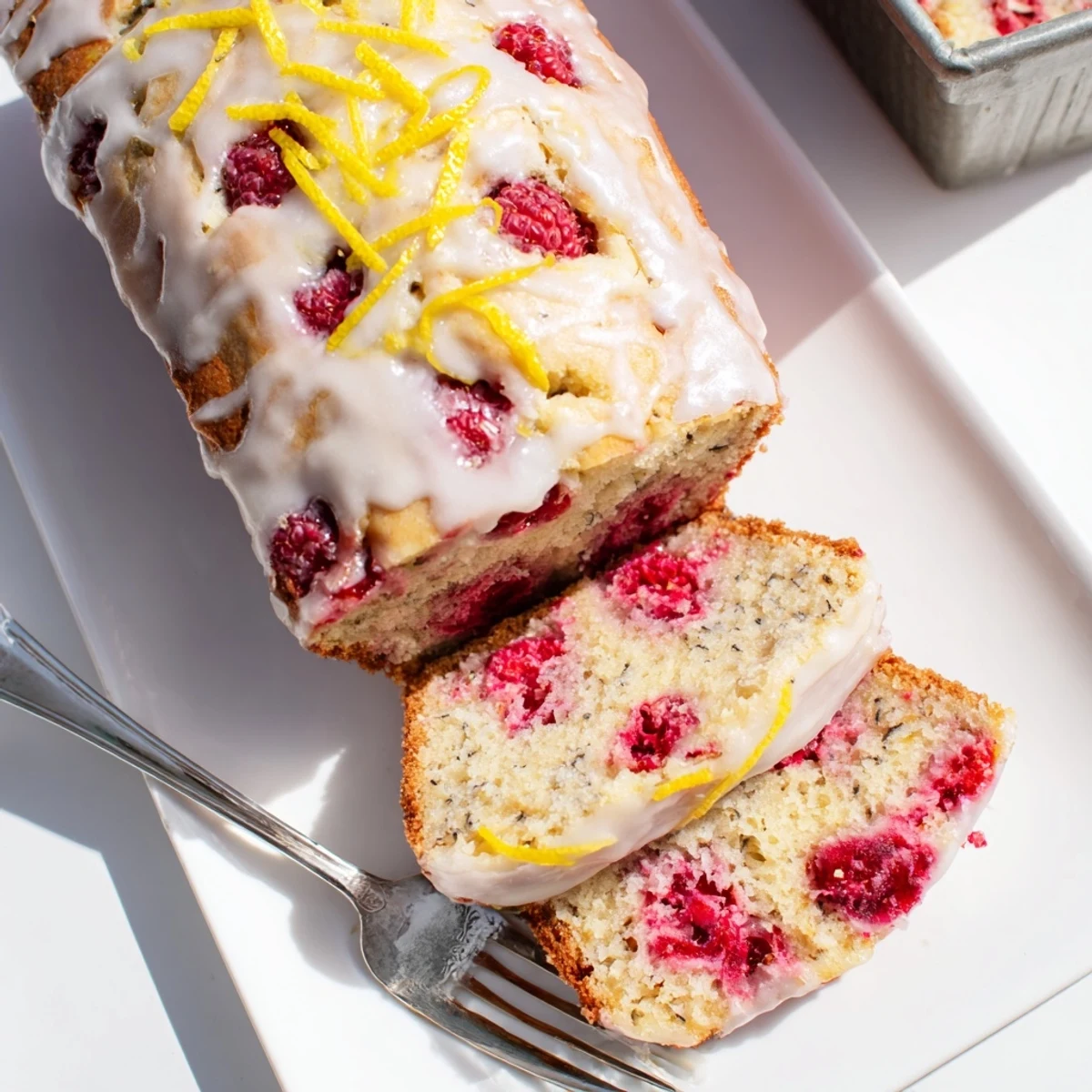 Sliced raspberry lemon poppyseed loaf cake revealing juicy red berries and scattered poppy seeds