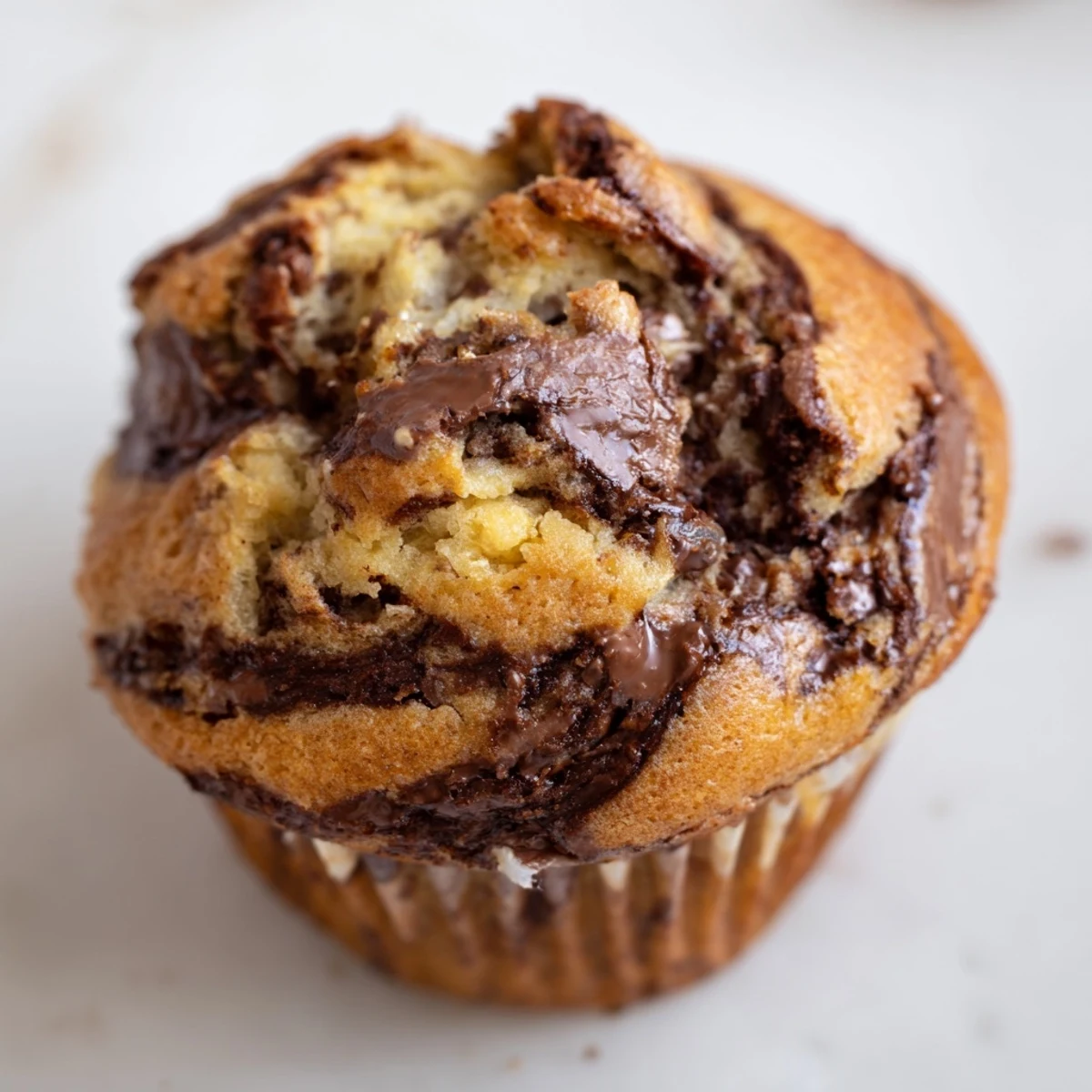 Freshly baked banana muffins featuring ribbons of creamy Nutella throughout the moist crumb