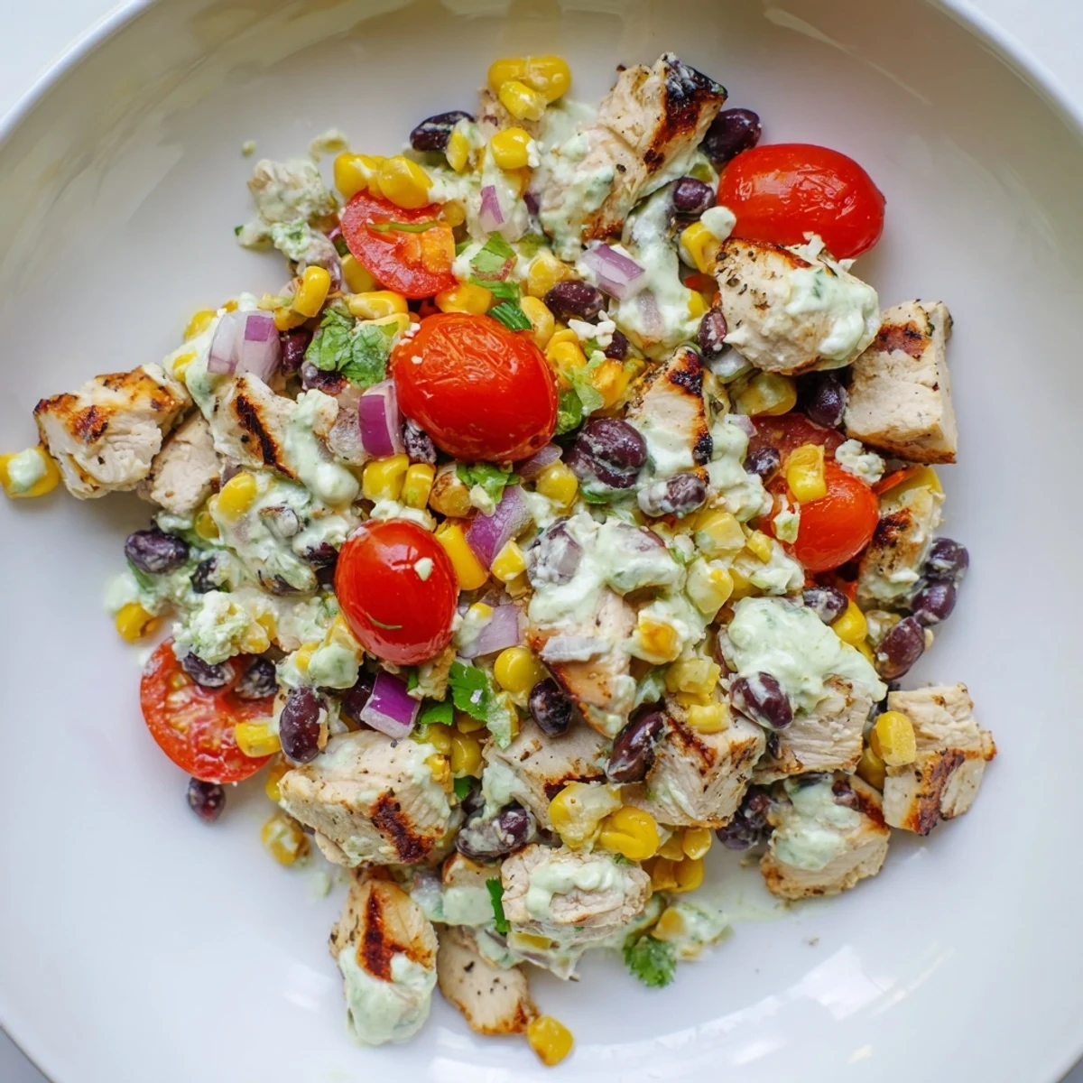 Close up of Mexican inspired high protein chicken street corn salad with juicy tomatoes and zesty lime wedges