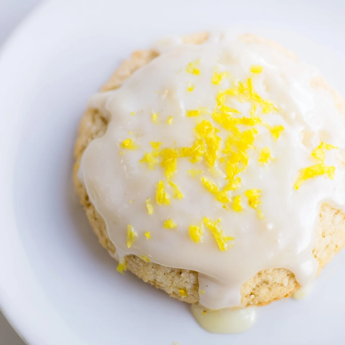 Soft lemon frosted cookies topped with tangy white glaze on a white plate