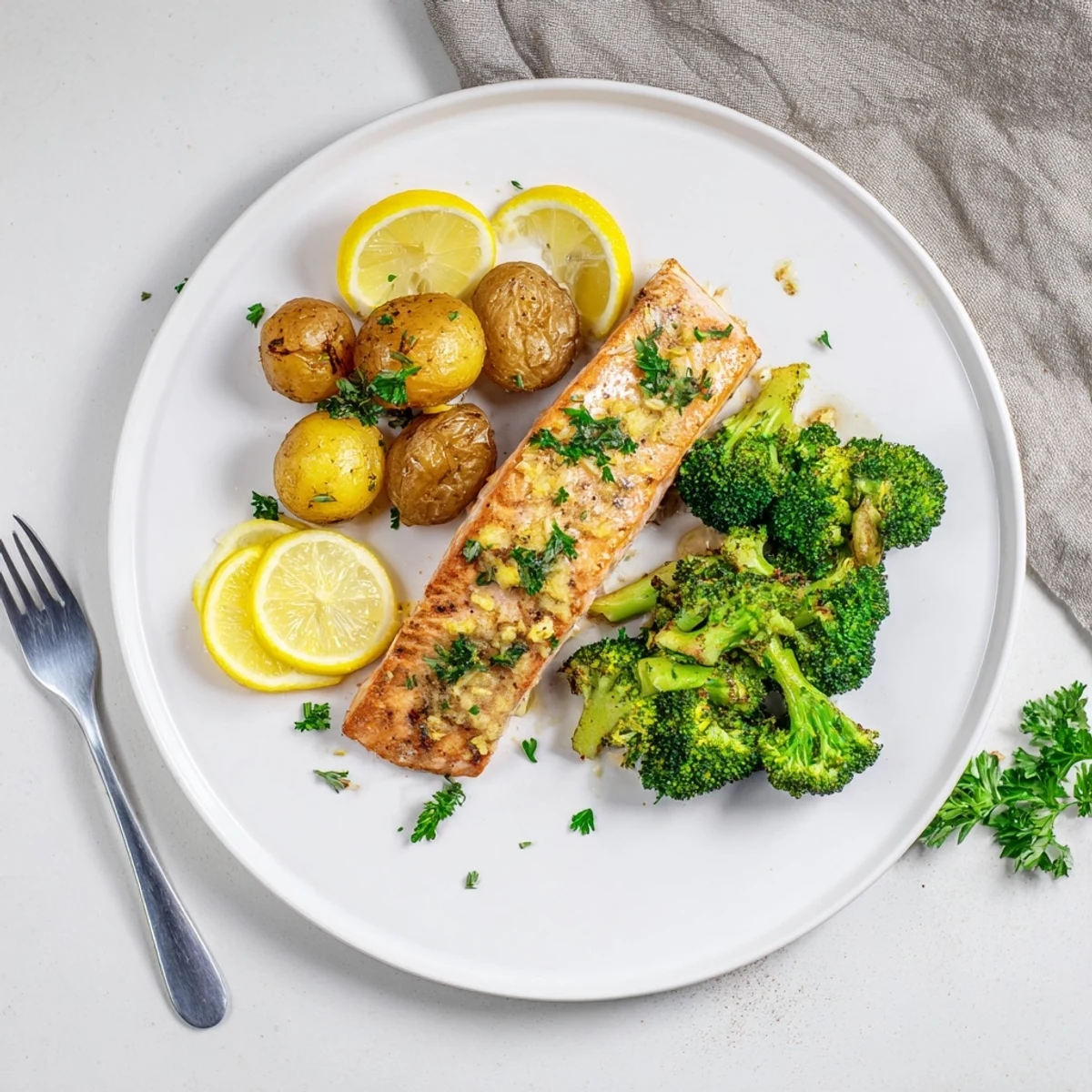 Flaky salmon glazed in creamy lemon butter sauce served with golden brown roasted potatoes and steamed broccoli on a ceramic dinner plate