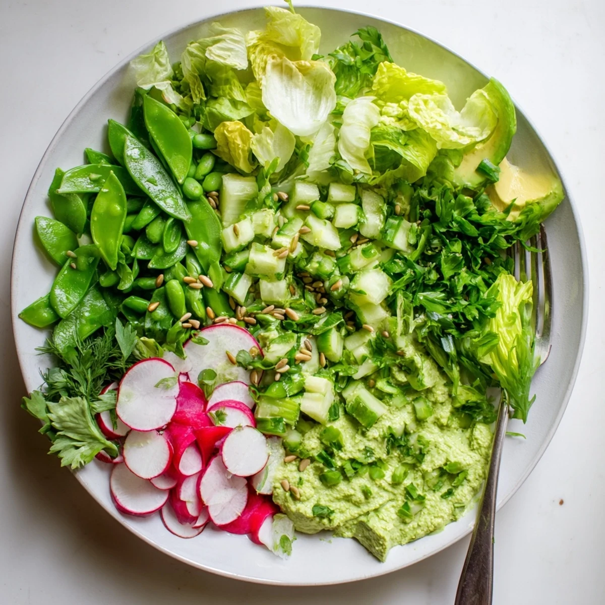 Bowl of fresh green goddess salad with crisp lettuce, avocado, cucumber, and creamy herb dressing