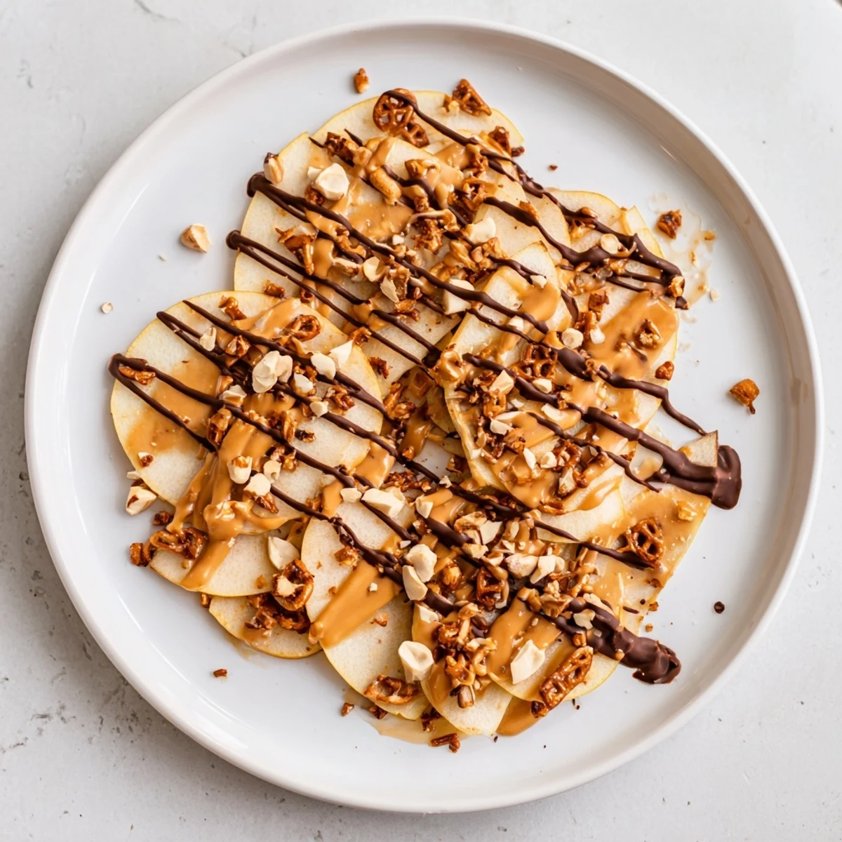 Colorful apple nachos platter featuring peanut butter swirls and chocolate with pretzel and coconut toppings