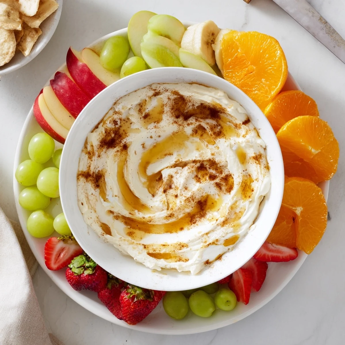 Wholesome yogurt-based dessert dip featuring marbled cinnamon topping on a platter surrounded by crisp apple slices, pears, and fresh berries