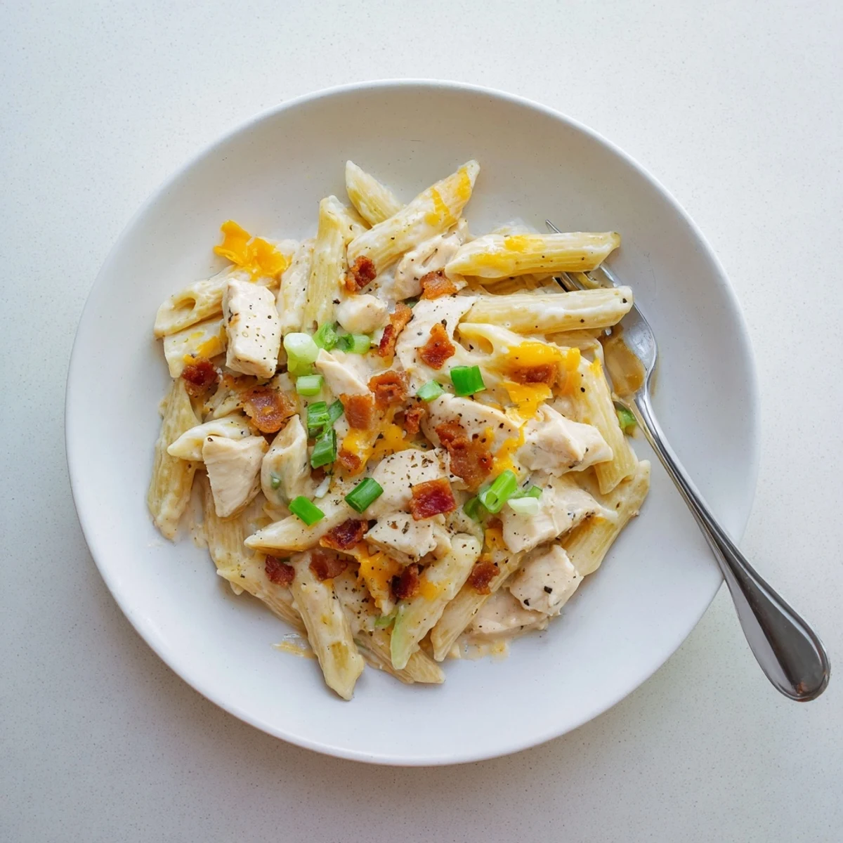 Hearty comfort food bowl featuring cheesy bacon ranch pasta with tender chicken pieces and black pepper