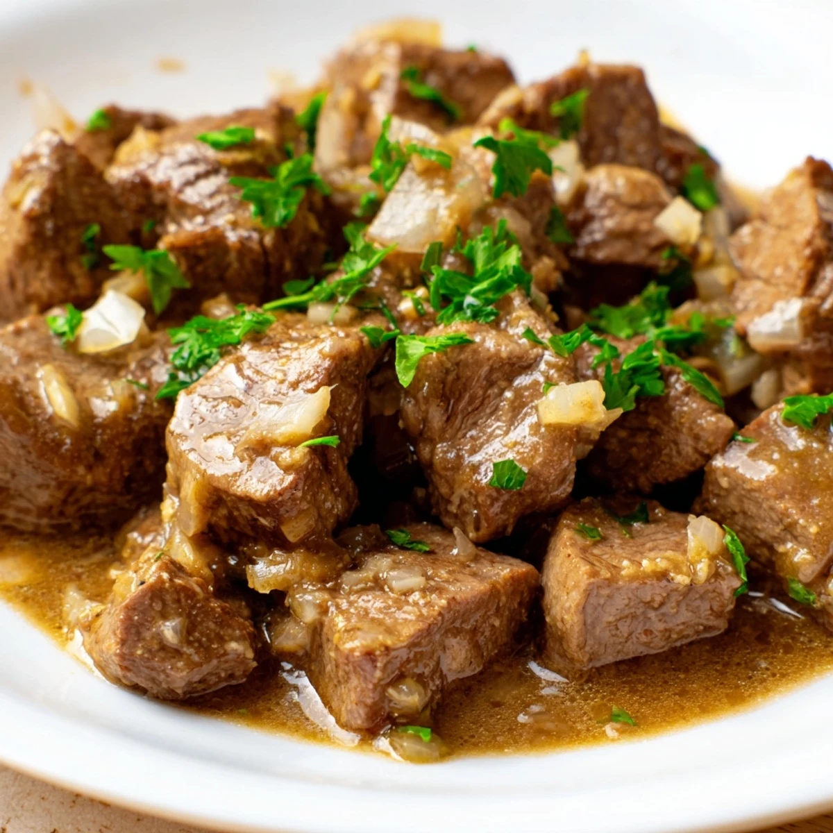 Tender Crockpot steak bites smothered in garlic butter sauce and garnished with fresh parsley