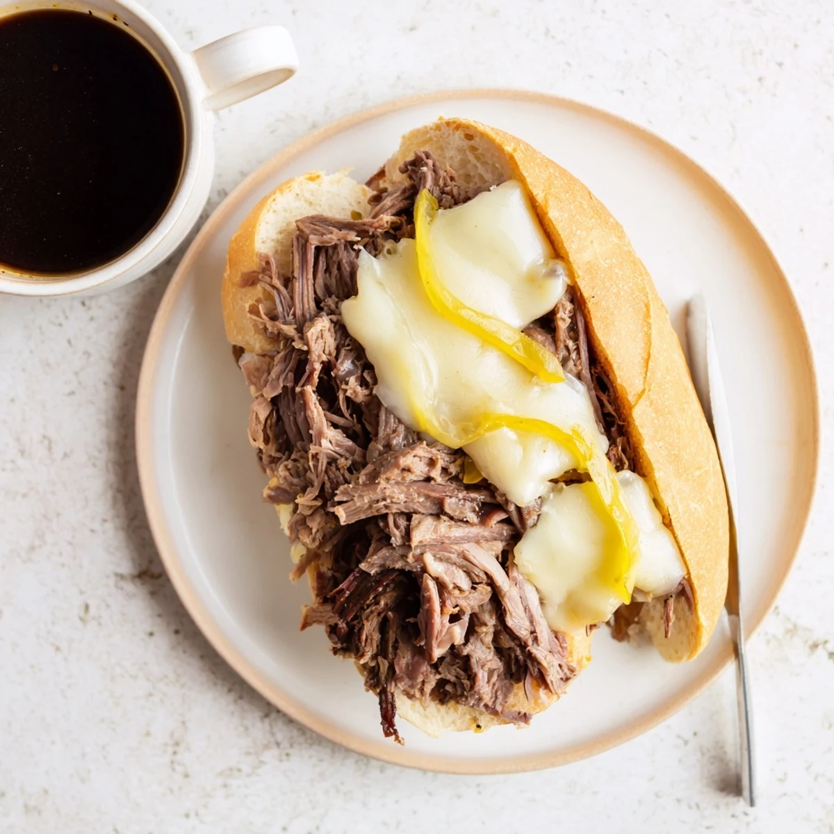 Golden Crockpot French Dip Sandwiches with melted cheese on toasted hoagie rolls beside rich au jus dipping sauce
