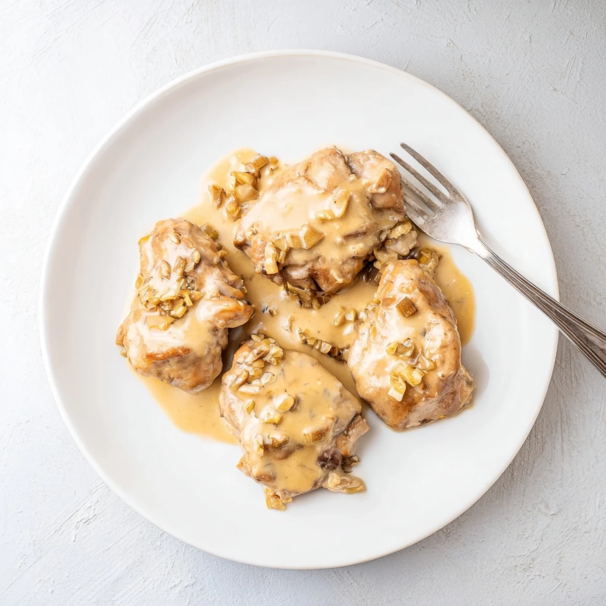 Creamy crockpot chicken thighs plated with luscious gravy and fresh parsley garnish