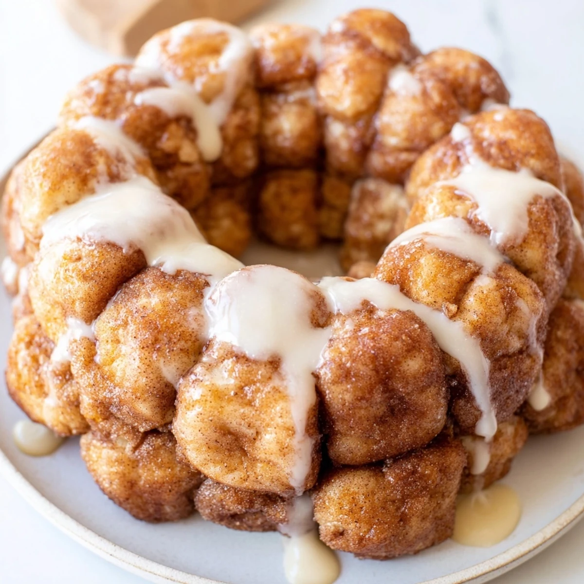 Golden high protein no sugar monkey bread with cinnamon coating drizzled with vanilla yogurt glaze