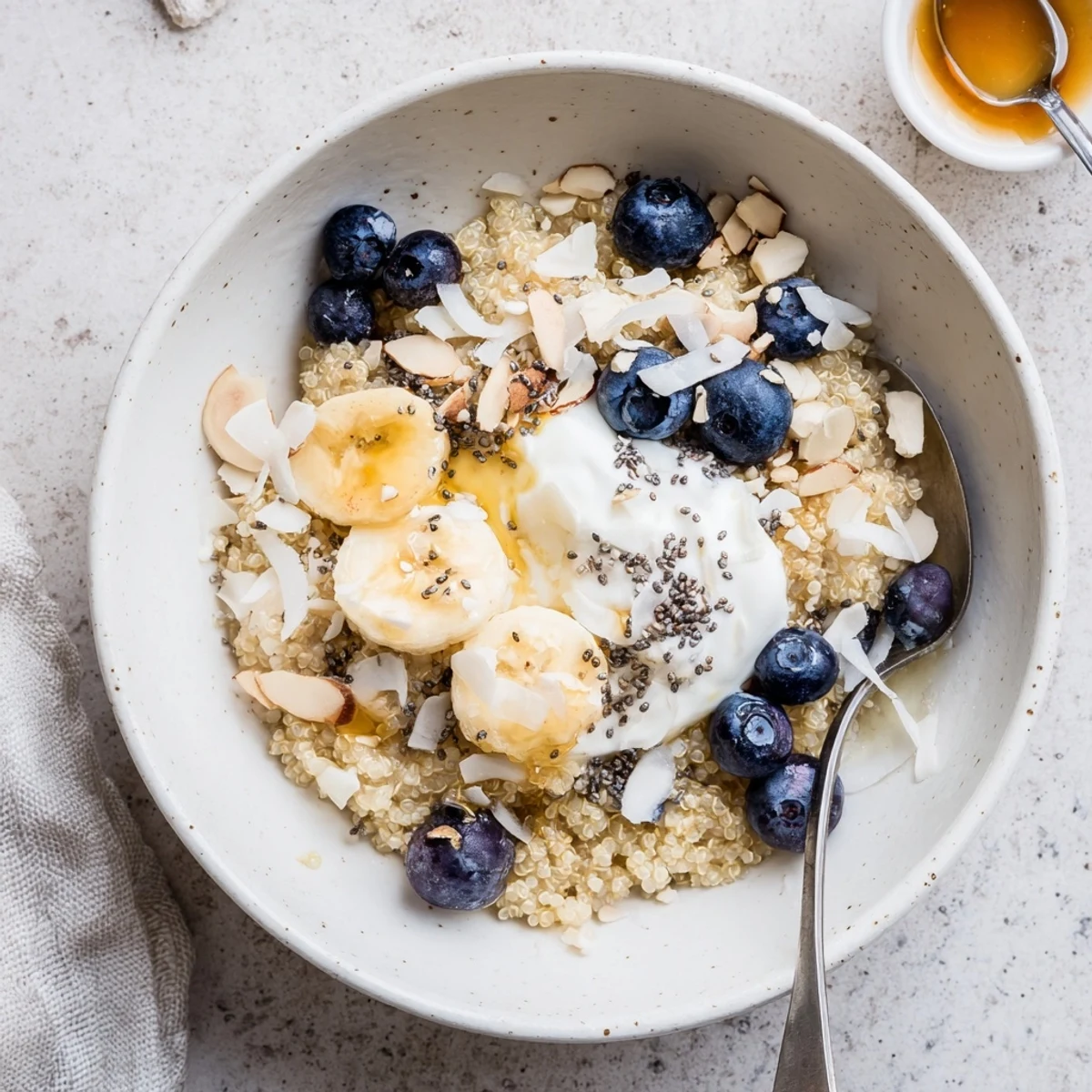 Creamy blueberry quinoa breakfast bowl arranged in a white serving dish with yogurt and shredded coconut