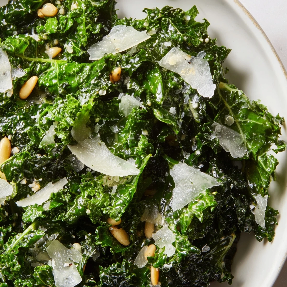 Fresh garlic lemon Parmesan kale salad in a rustic wooden bowl with shaved cheese