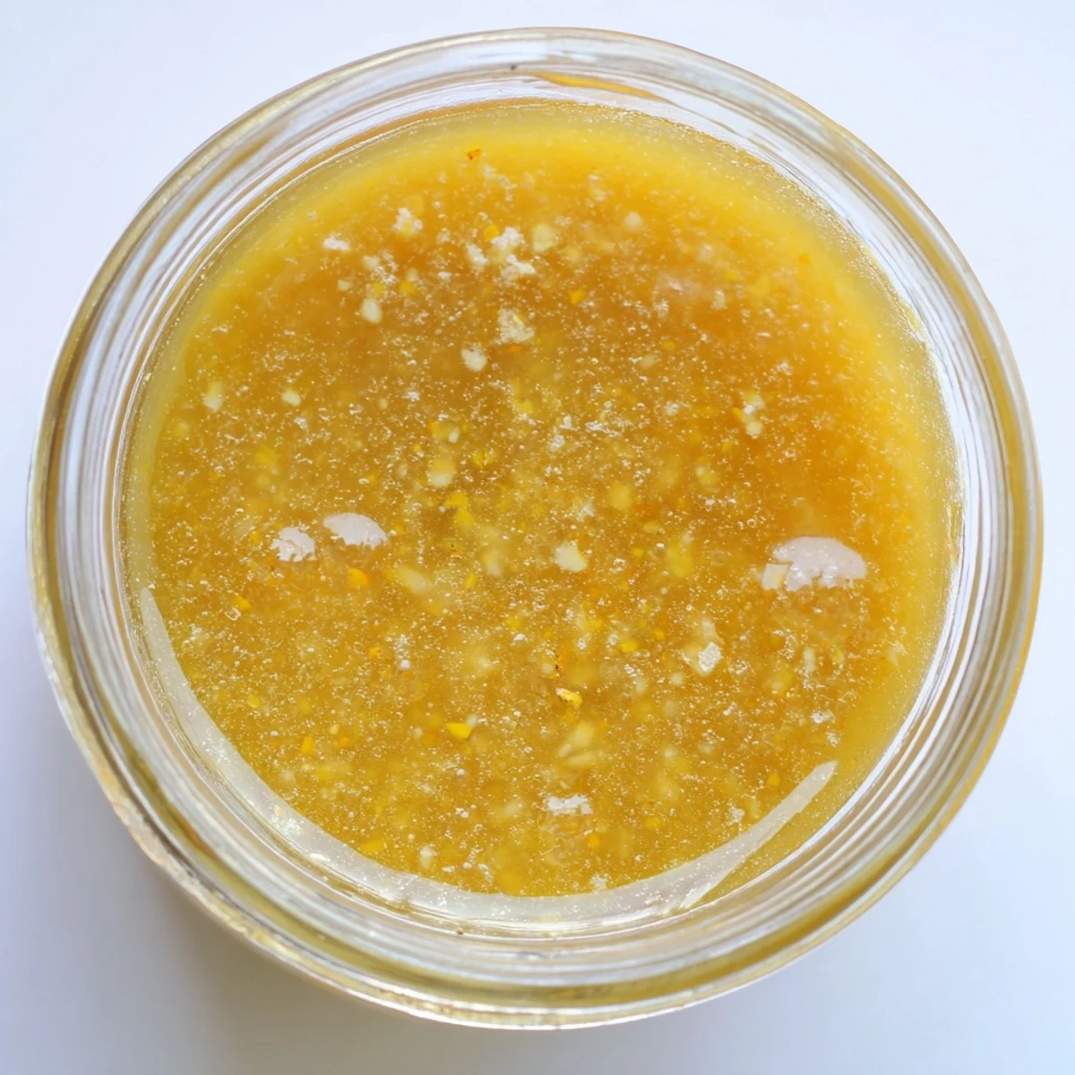 Golden citrus vinaigrette emulsified in a glass jar ready for drizzling over fresh salads