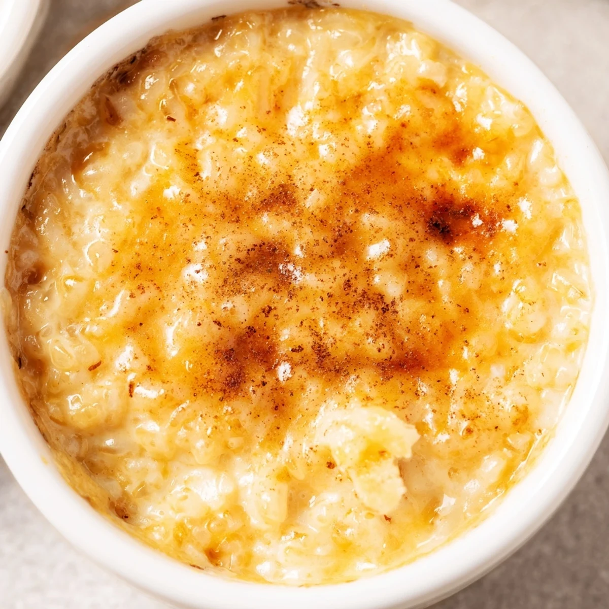 Creamy Portuguese rice custard in ramekins topped with golden cinnamon-sugar sprinkles