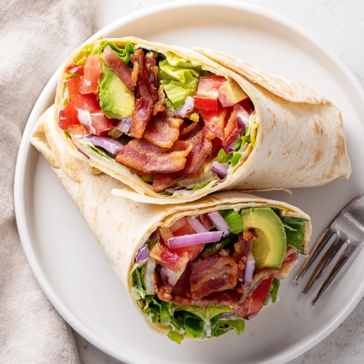 Stacked Meal Prep BLT Wraps sliced showing crunchy lettuce, warm tortilla, avocado