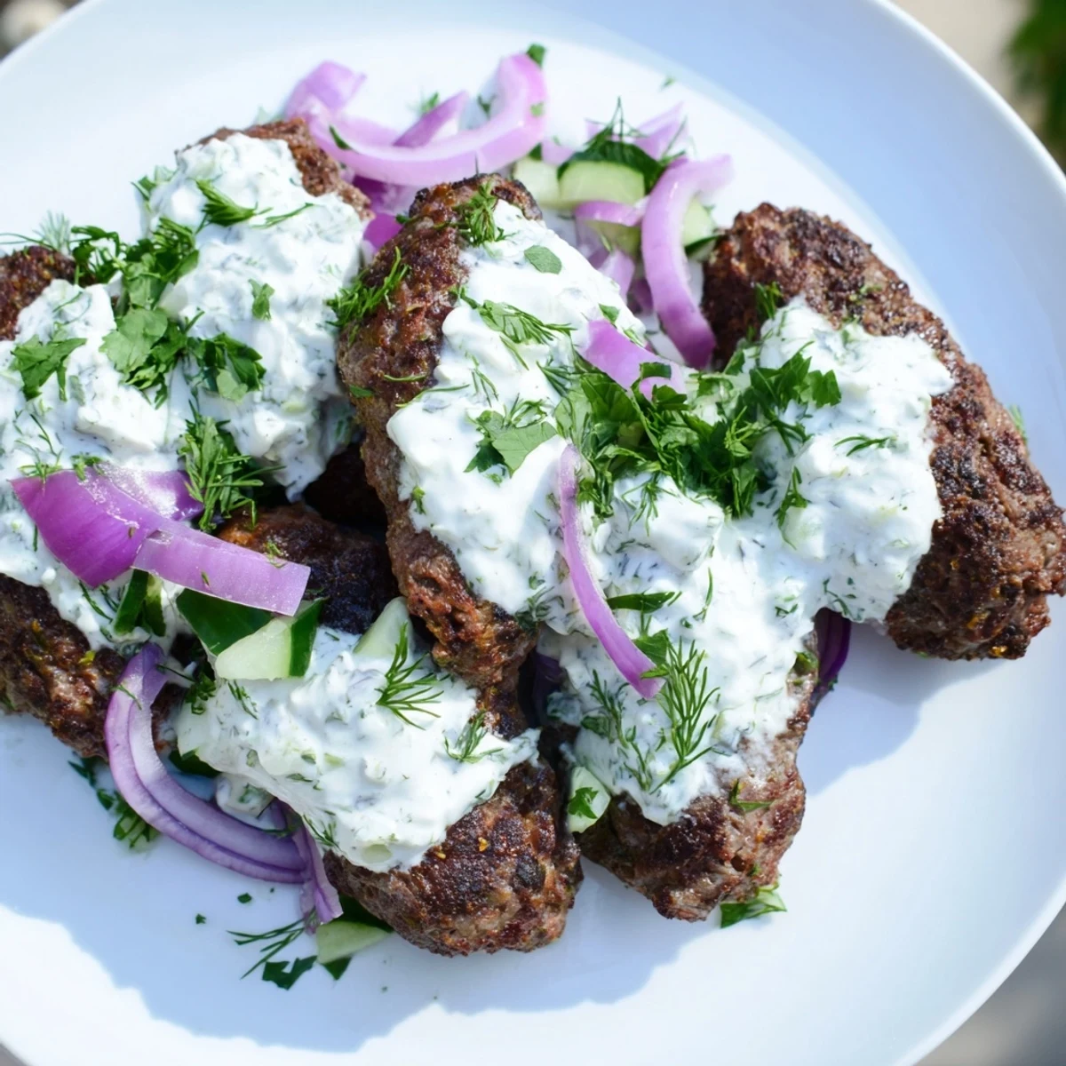 Golden brown smashed beef kebabs served with cool cucumber yogurt sauce and fresh herbs