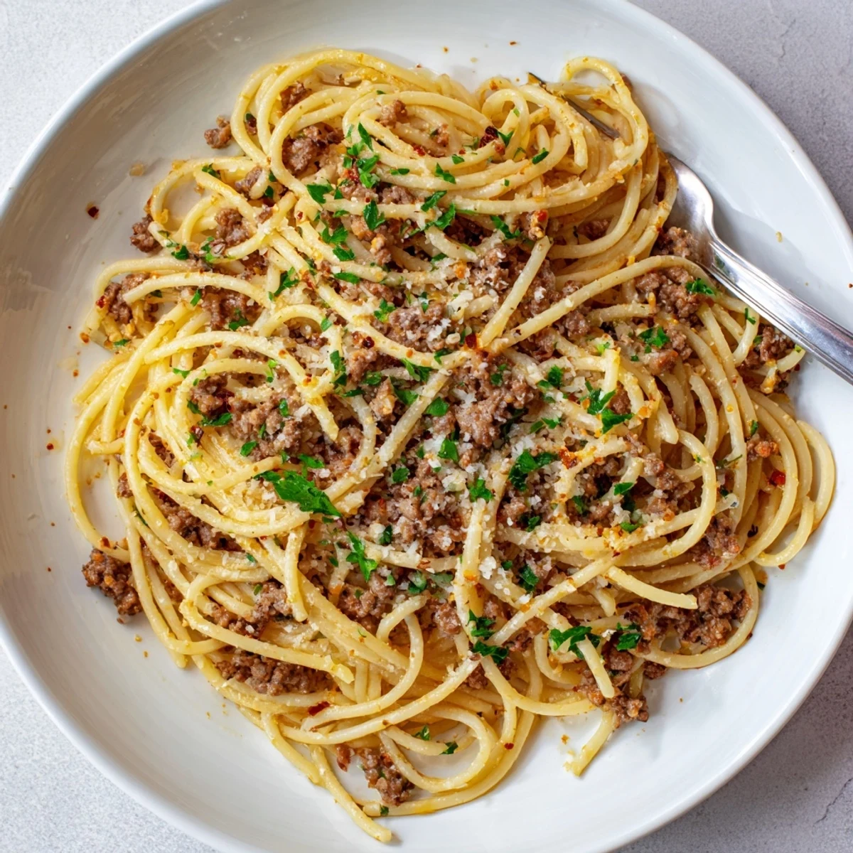 Golden garlic butter pasta with ground beef topped with fresh parsley and Parmesan cheese