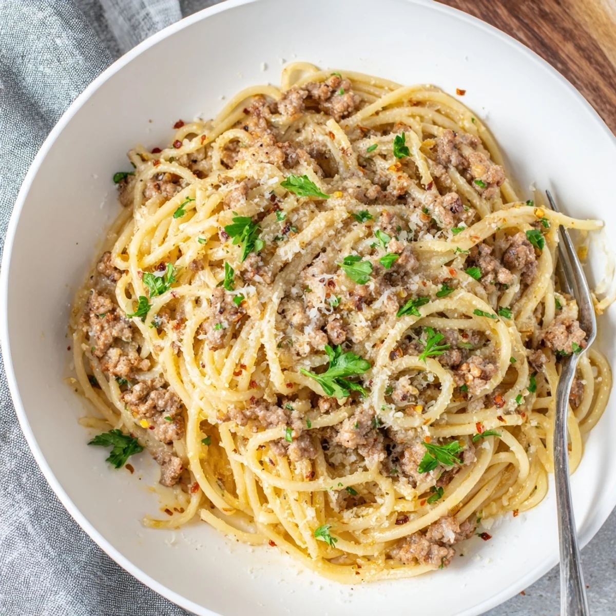 Steaming plate of garlic butter pasta with ground beef coated in a rich, silky sauce