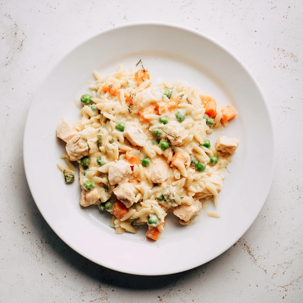 Savory one-pot Creamy Chicken Pot Pie Orzo with peas, carrots, and melted cheese garnish.