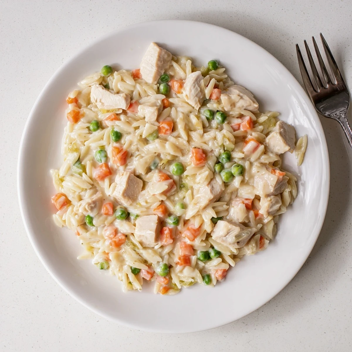 A steaming bowl of Creamy Chicken Pot Pie Orzo topped with fresh parsley and parmesan.