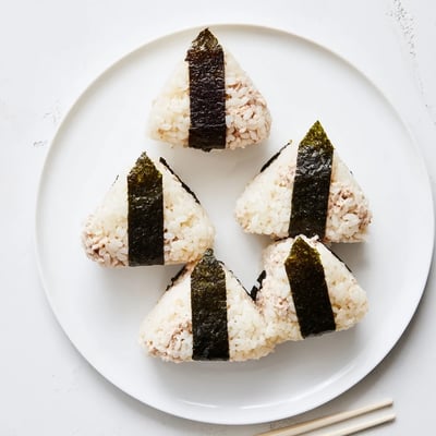 Handheld Japanese rice ball stuffed with creamy tuna mayonnaise filling for lunchbox