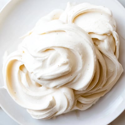 Smooth Italian meringue buttercream spread evenly across golden cupcakes with swirled peaks