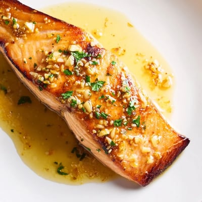 Crispy seared garlic butter salmon drizzled with melted sauce and fresh parsley