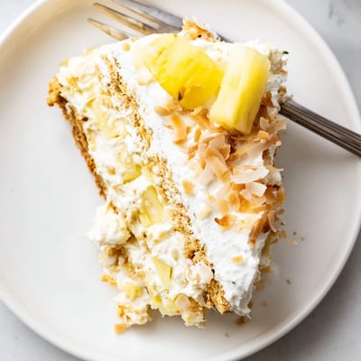 Golden toasted coconut tops a chilled no bake pineapple coconut cream cake with buttery crust